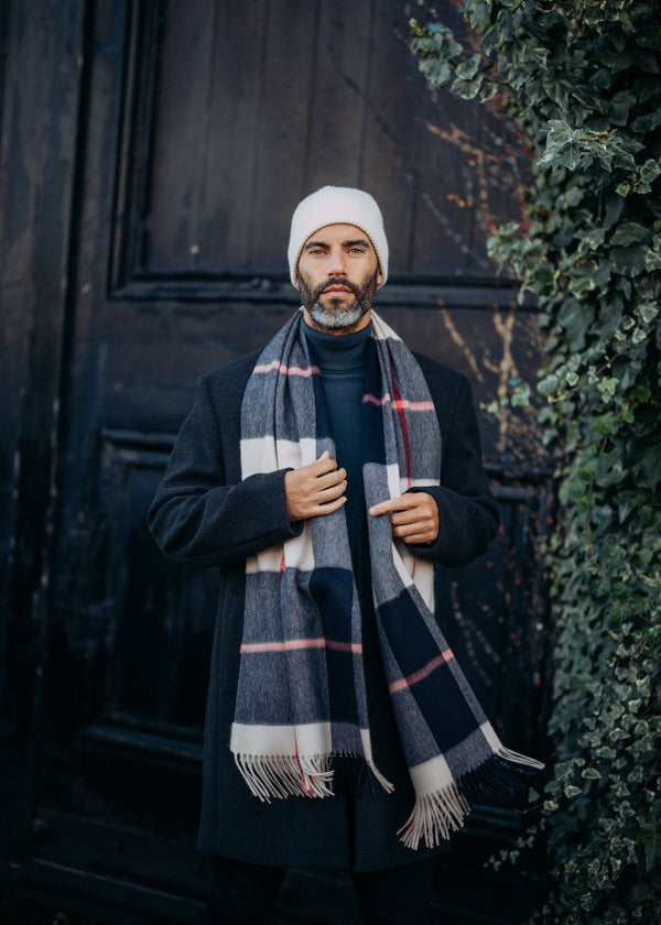 Man wearing a black coat, white beanie, and plaid cashmere scarf