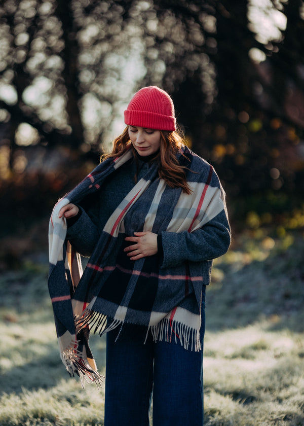 Woman wearing a red cashmere beanie and striped cashmere scarf 