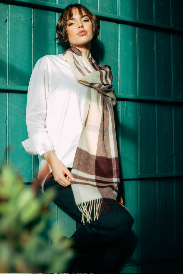 Woman wearing a plaid cashmere scarf against a teal wooden background