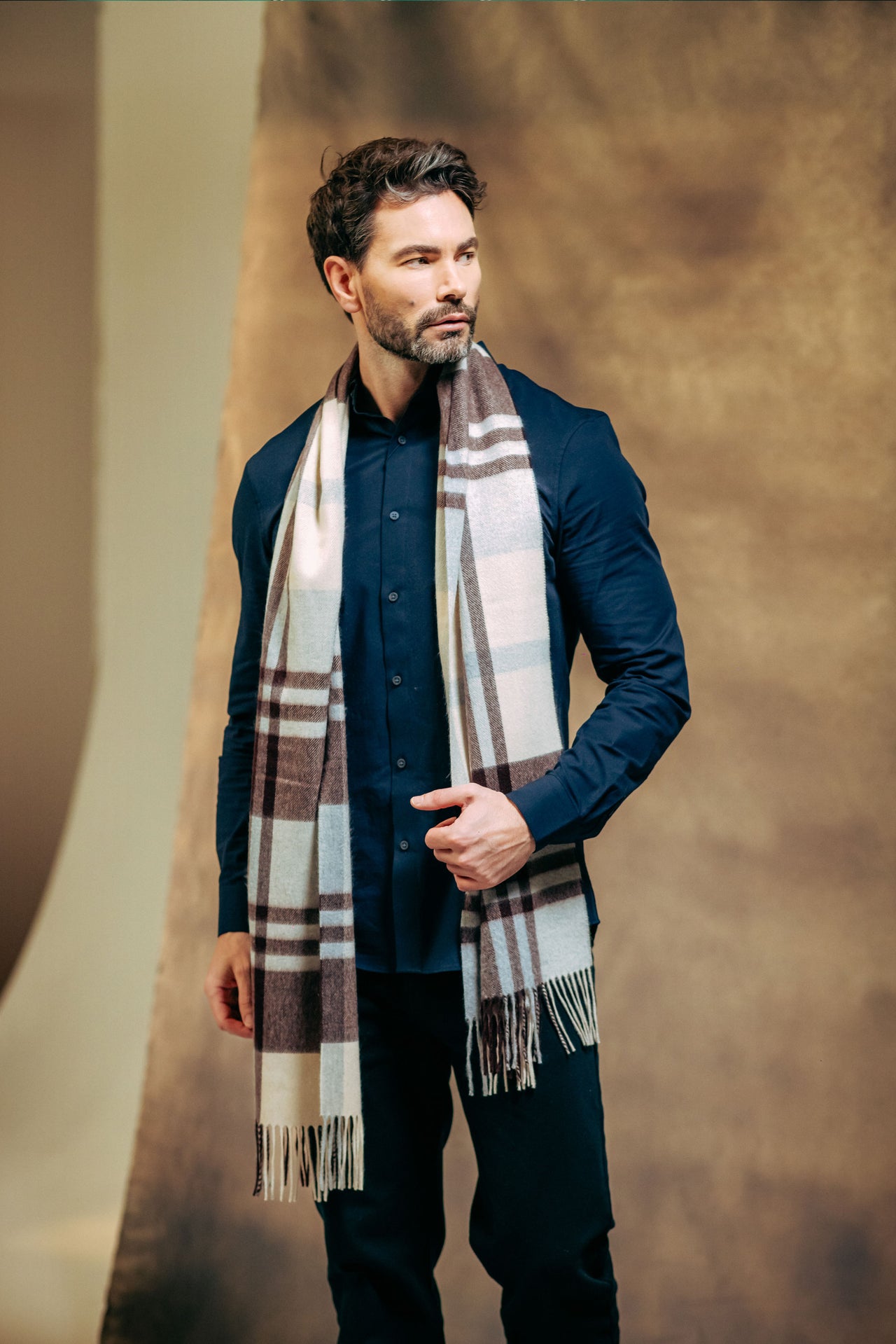 Man wearing a plaid cashmere scarf against a brown background