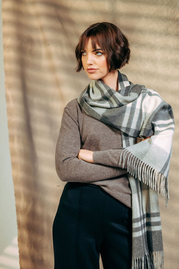 Woman wearing a plaid cashmere scarf against a neutral background