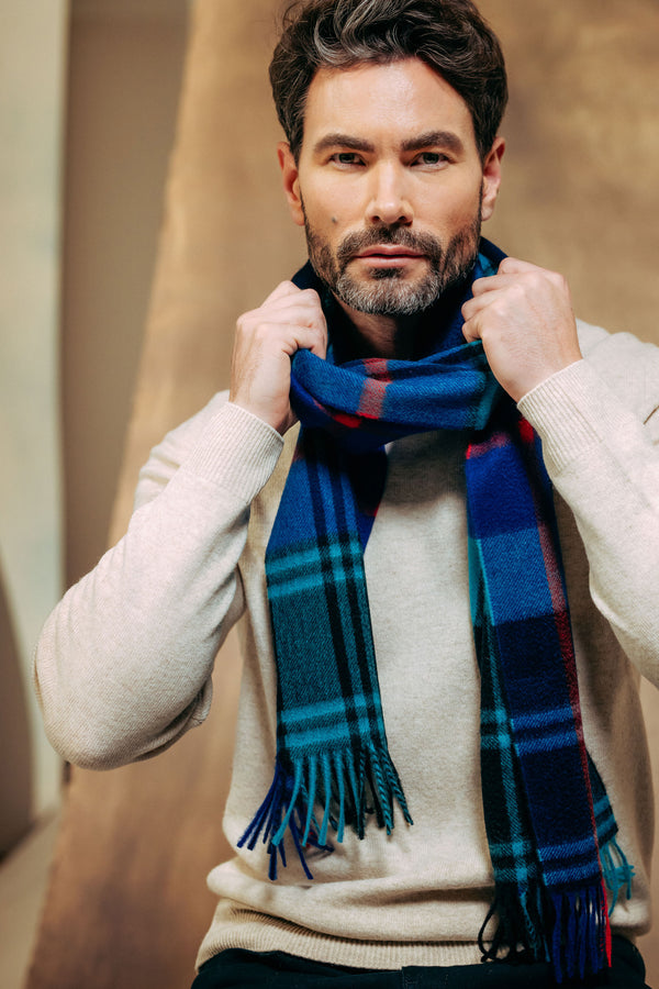 Man wearing a blue cashmere plaid scarf with a neutral background