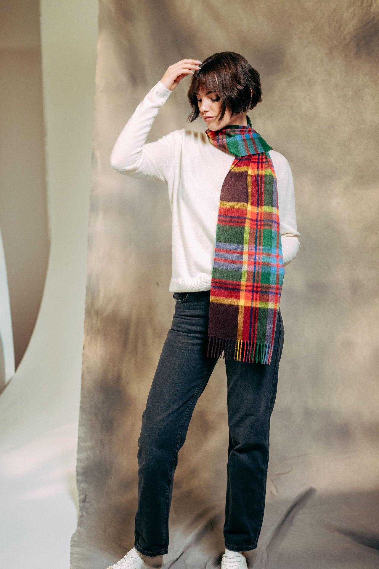 Person wearing a colorful plaid cashmere  scarf against a neutral background