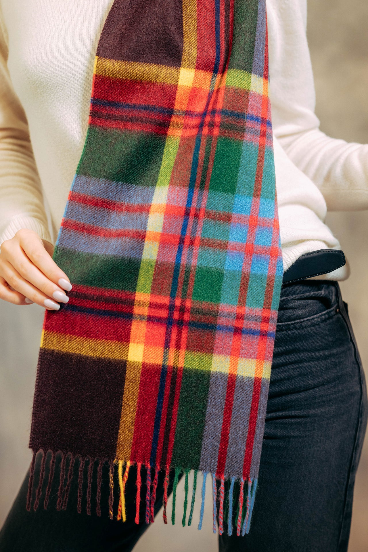 Person wearing a colorful plaid cashmere scarf with a neutral background