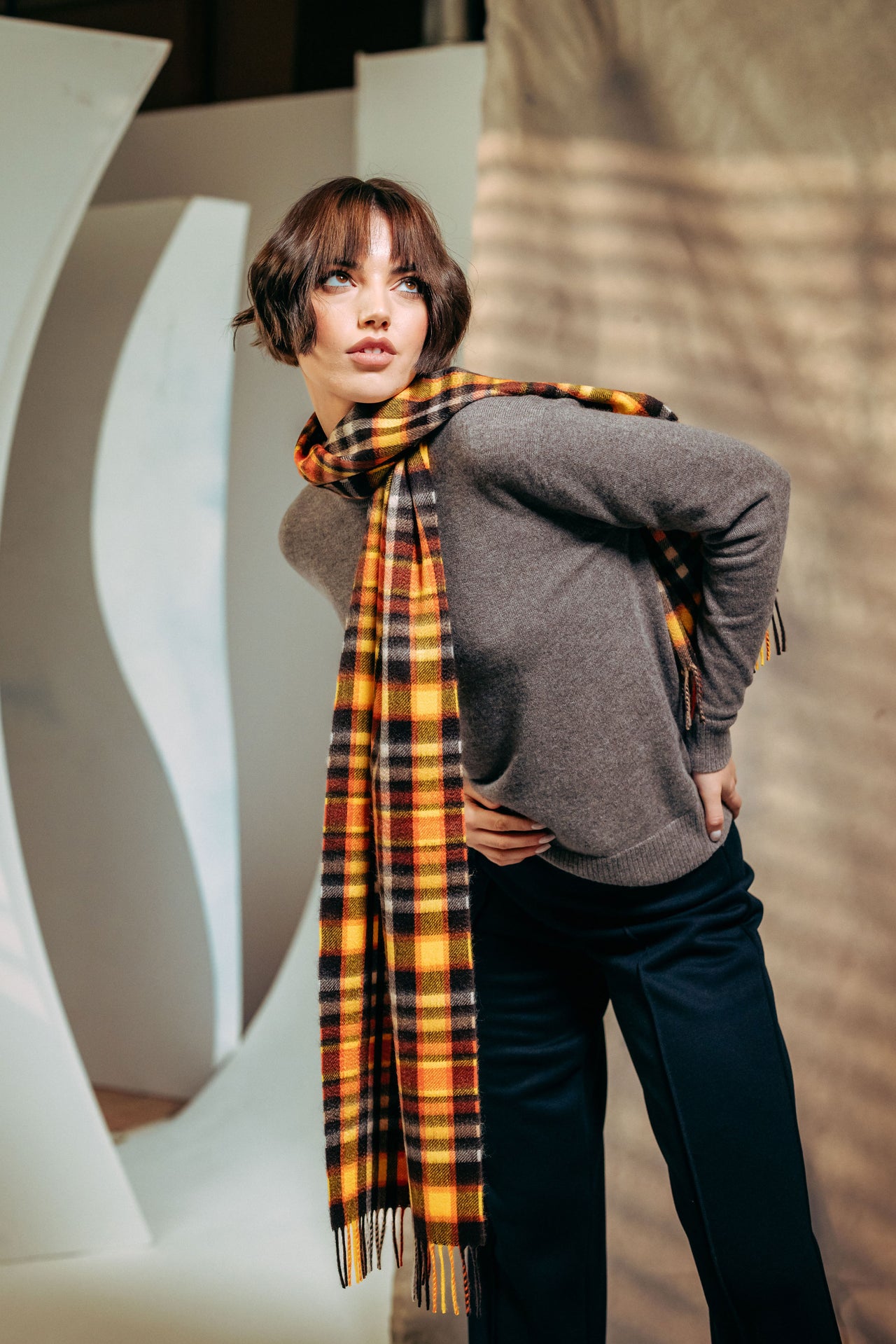 Woman wearing a plaid cashmere scarf and gray sweater in an urban setting