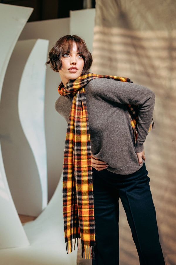 Woman wearing a plaid cashmere scarf and gray sweater in an urban setting