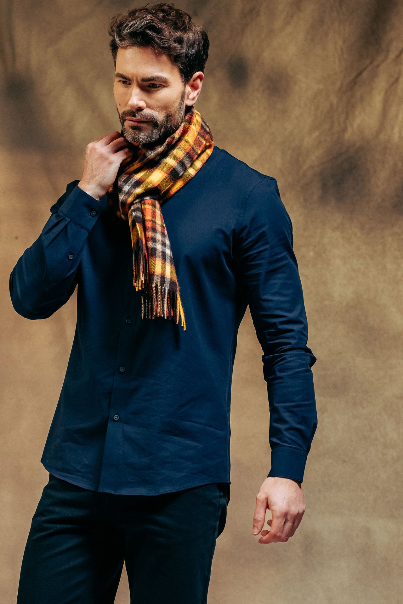 Man wearing a blue shirt and plaid cashmere scarf against a brown background