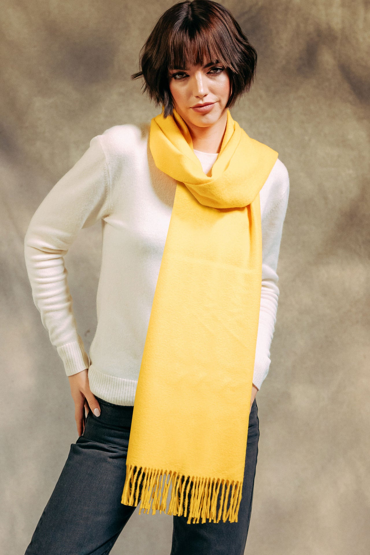 Woman wearing a yellow cashmere scarf with a plain background