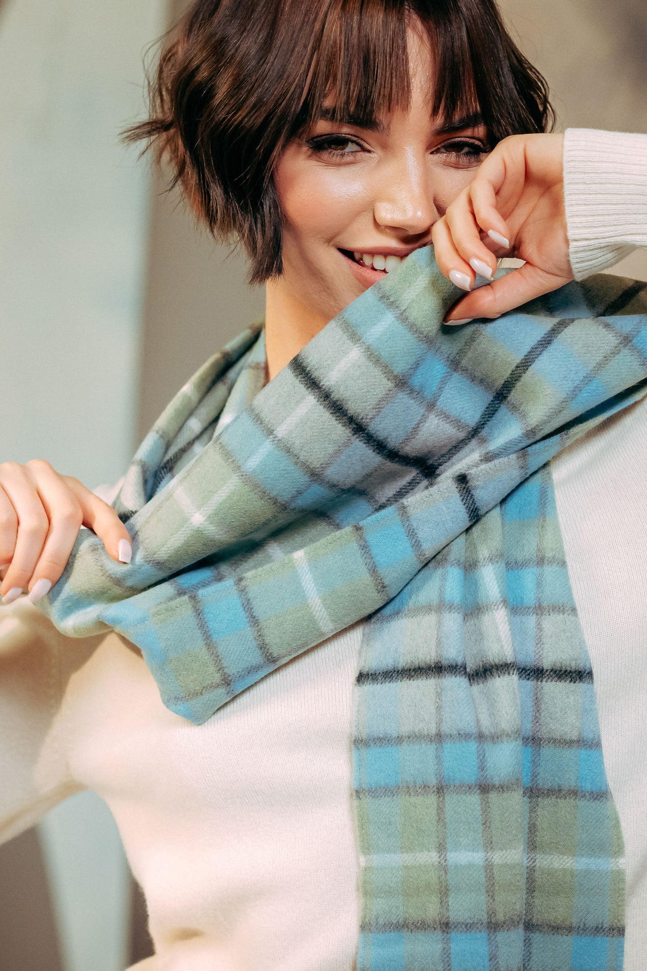 Woman wearing a blue and green plaid scarf with a blurred background