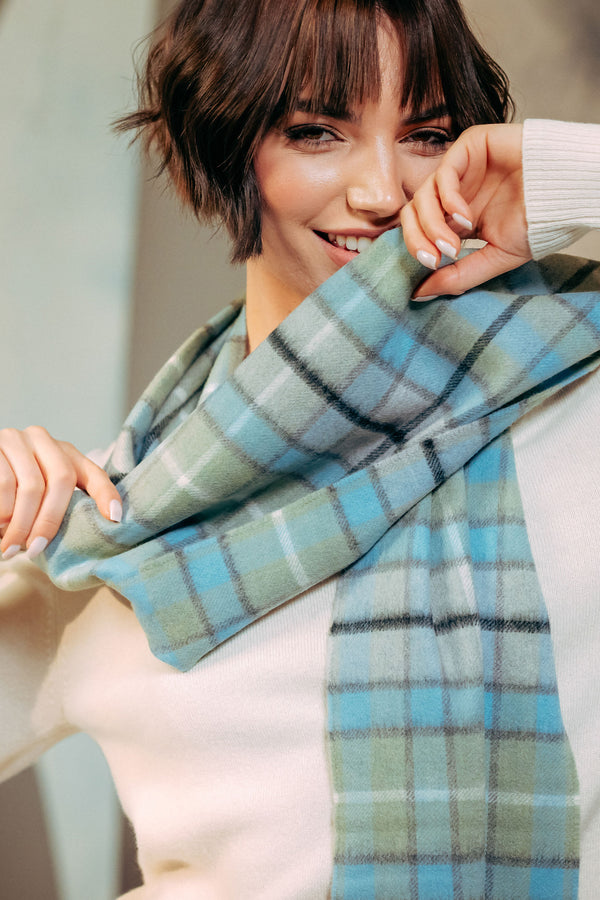 Woman wearing a blue and green plaid scarf with a blurred background