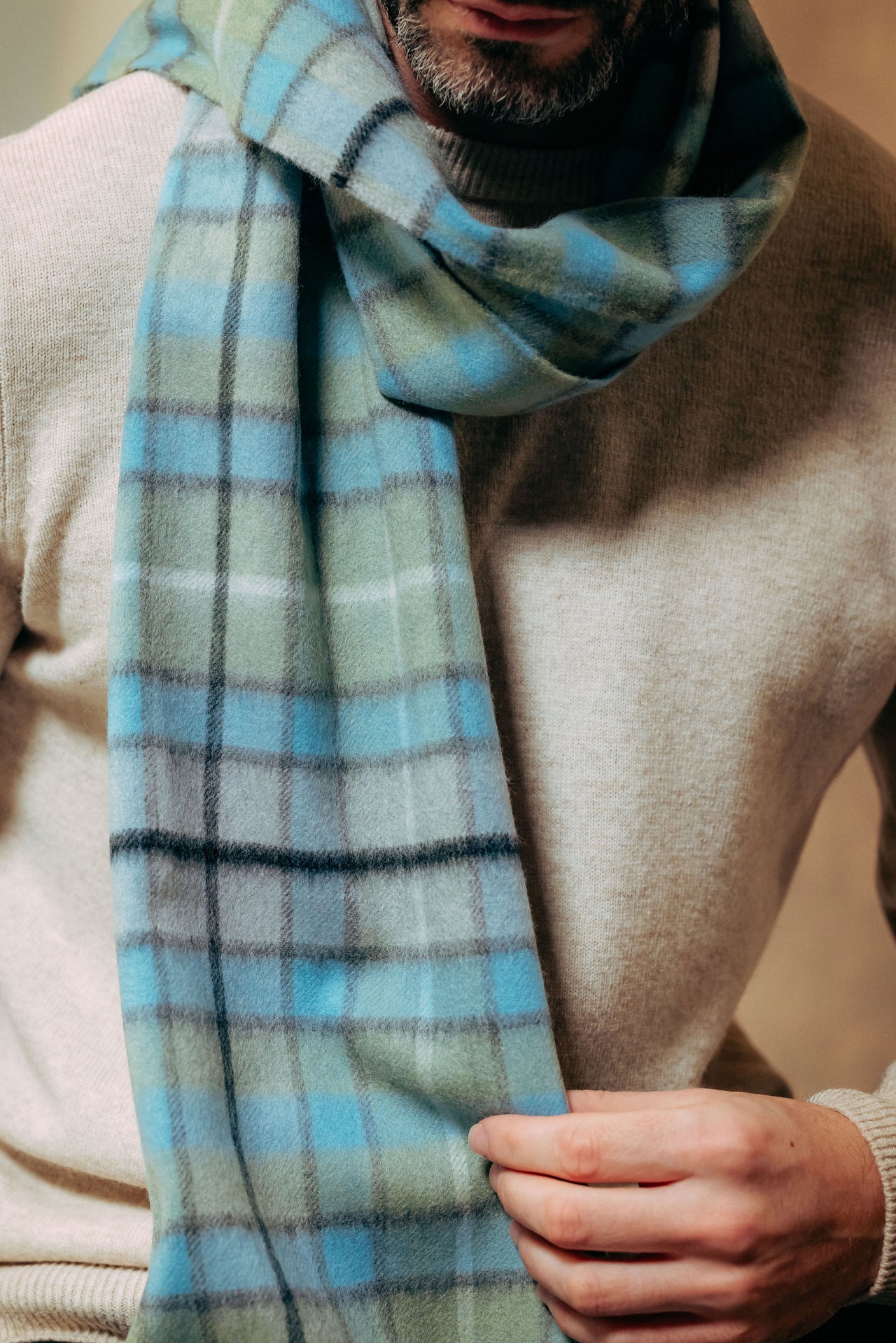 Person wearing a plaid scarf with a neutral background