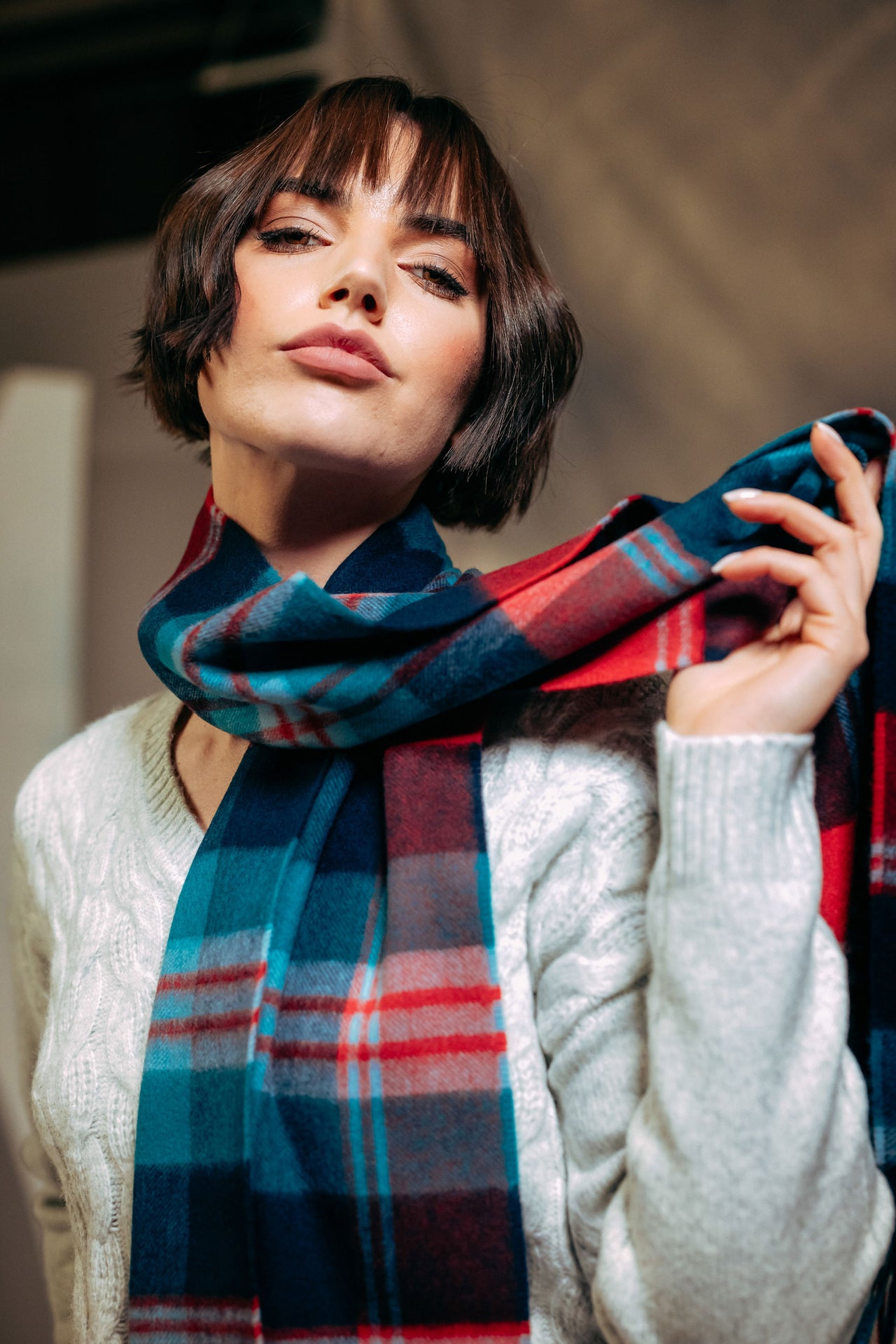 Woman wearing a plaid cashmere  scarf with a neutral background
