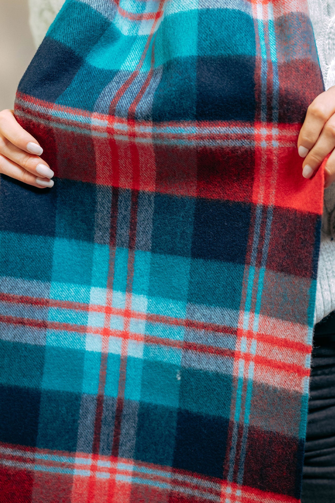 Close-up of a plaid cashmere scarf with red, blue, and white colors.