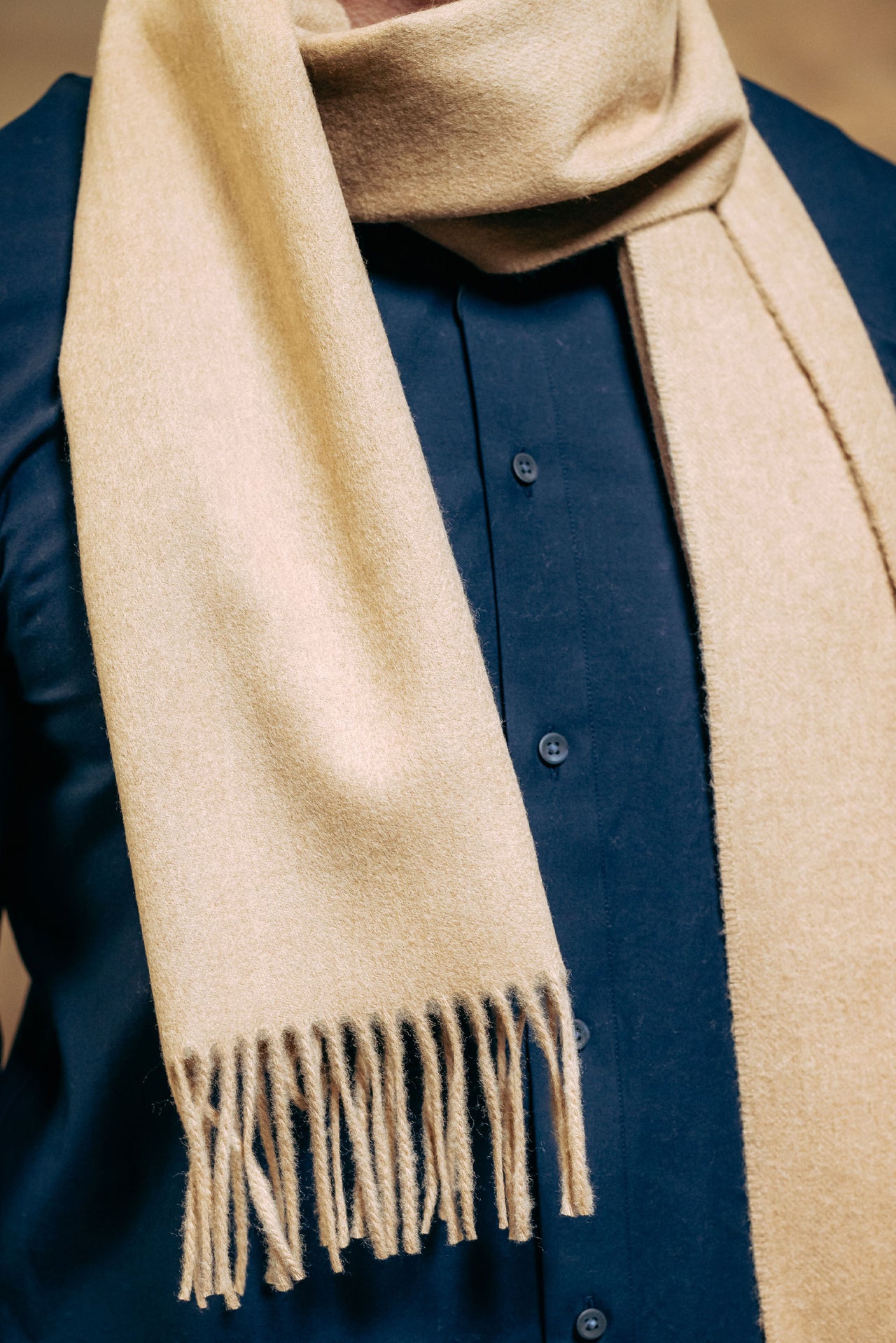 Beige scarf draped over male model wearing a blue shirt.
