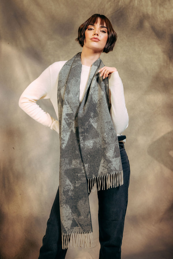 Woman wearing a long, patterned cashmere scarf against a textured brown background