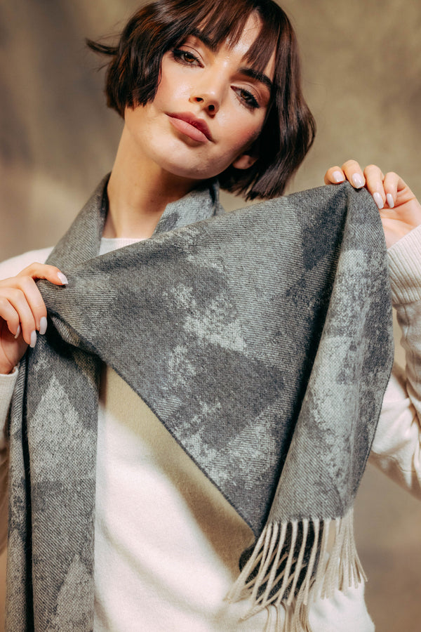 Woman wearing a gray checkered cashmere  scarf with fringe, against a neutral background