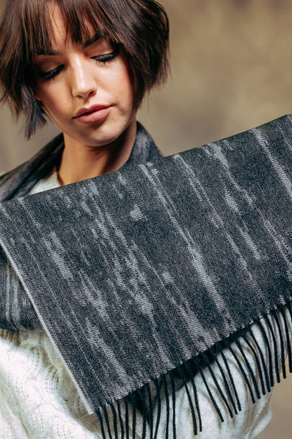 Woman wearing a dark gray cashmere scarf with fringe details